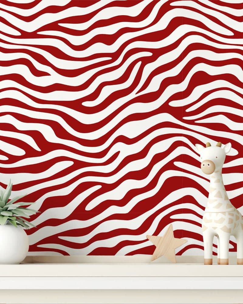 White and red zebra striped wall with a small giraffe figurine and plant.