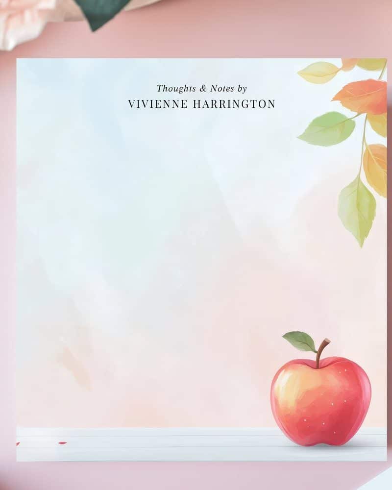 Red apple on notepad with autumn leaves and Vivienne Harrington's name.