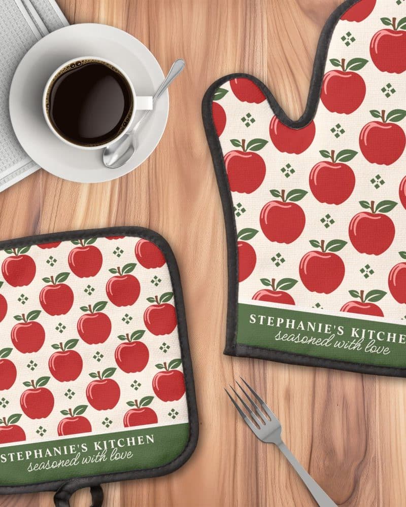 A kitchen oven mitt and pot holder with a red apple pattern and personalized text.