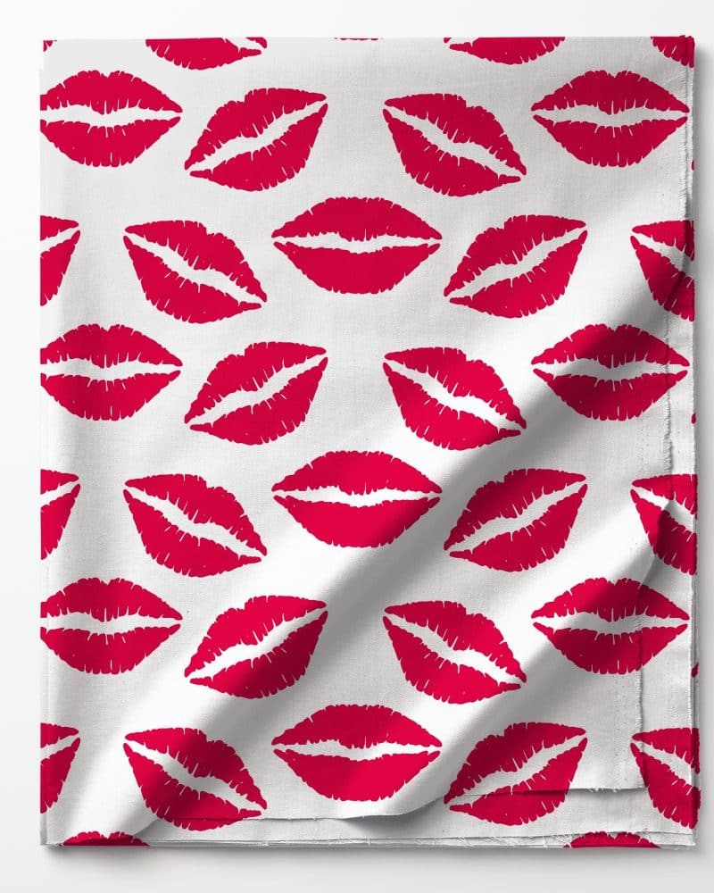 White fabric with a repeating pattern of red lipstick kisses.