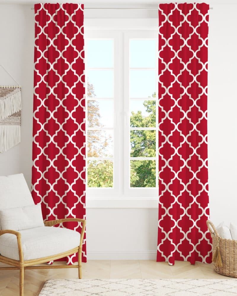 Red curtains with a white quatrefoil pattern hang in front of a window.