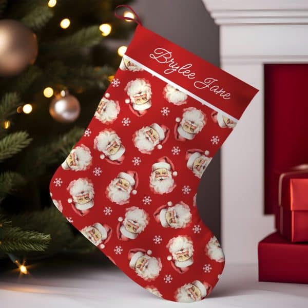 Personalized Red Christmas Stocking With A Repeating Pattern Of Santa Claus Faces And Snowflakes. The Name Brylee Jane Is Embroidered On The Cuff.