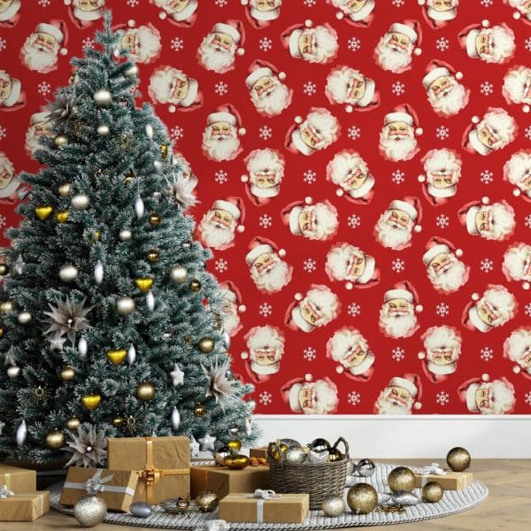Decorated Christmas Tree In Front Of Red Wallpaper Featuring A Repeating Pattern Of Santa Claus Faces.