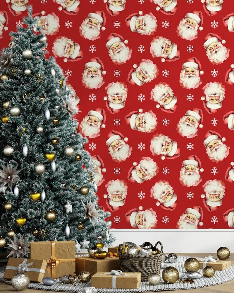 Decorated Christmas tree in front of red wallpaper featuring a repeating pattern of Santa Claus faces.