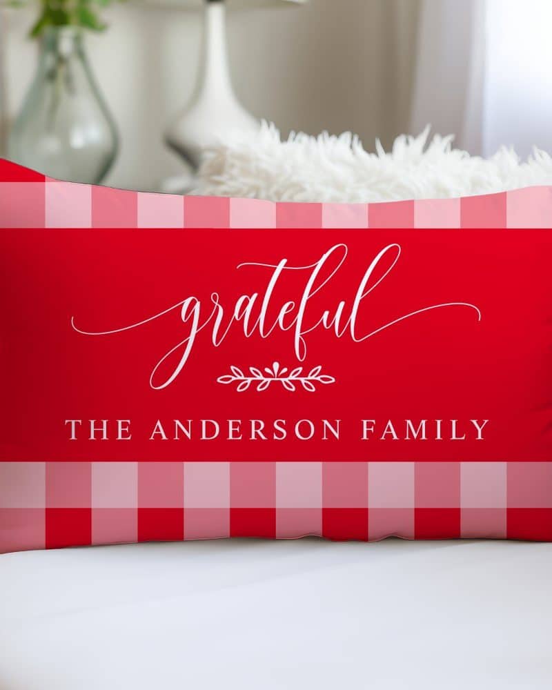 Red and pink gingham pillow with the word grateful in a script font and the text The Anderson Family.