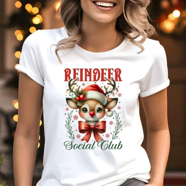 White T-Shirt Featuring A Cute Cartoon Reindeer Wearing A Santa Hat And Red Bow, Surrounded By Holiday Decorations; Text Reads Reindeer Social Club.