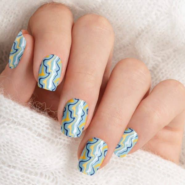 Close-Up Of A Hand With Light Blue And Yellow Wavy Nail Polish.