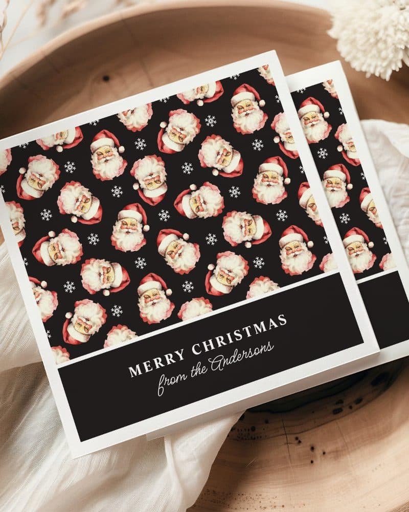 A Christmas card with a repeating pattern of Santa Claus faces on a black background. The card reads Merry Christmas from the Andersons.