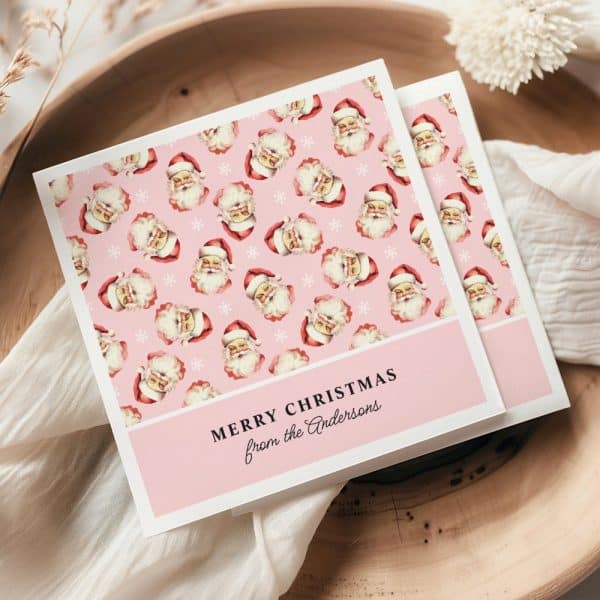 Pink Christmas Card With A Repeating Pattern Of Santa Claus Faces And Snowflakes. The Card Is Personalized With &Quot;Merry Christmas From The Andersons.&Quot;