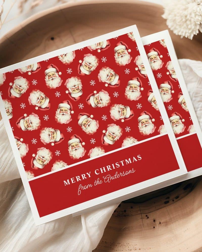 Christmas card with a red background and repeating pattern of Santa Claus faces. The card reads Merry Christmas from the Andersons.