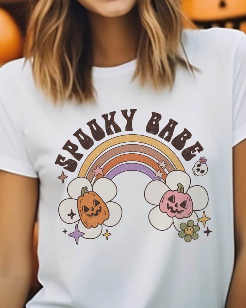 White t-shirt with Spooky Babe text above a rainbow graphic featuring two jack-o'-lanterns.