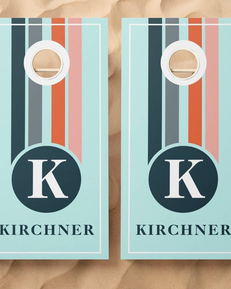 Pair of light blue cornhole boards with vertical stripes and a central monogrammed K. The name Kirchner is printed below.