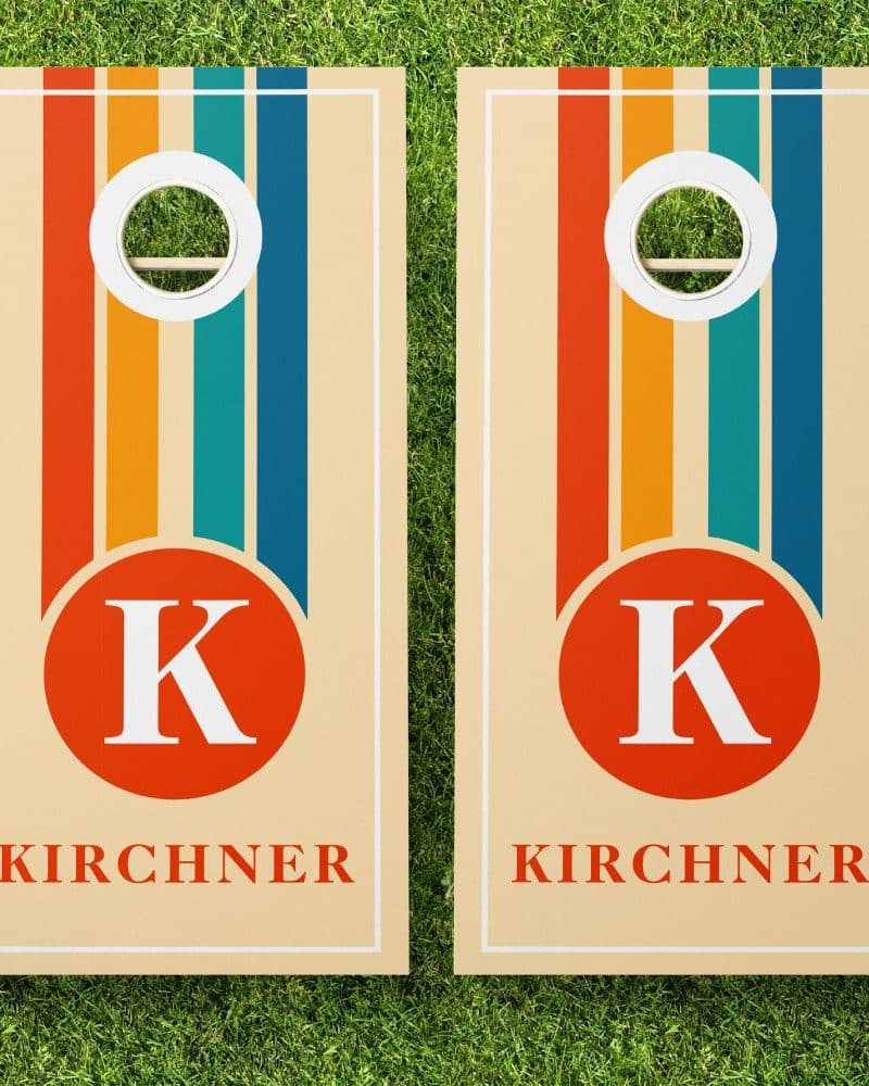 Pair of beige cornhole boards with vertical stripes and a central red circle containing the letter K and the name Kirchner.