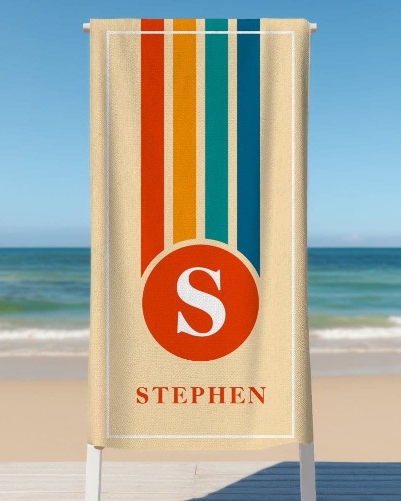 Beige beach towel with retro vertical stripes and a red circle containing the letter S, with the name Stephen below.
