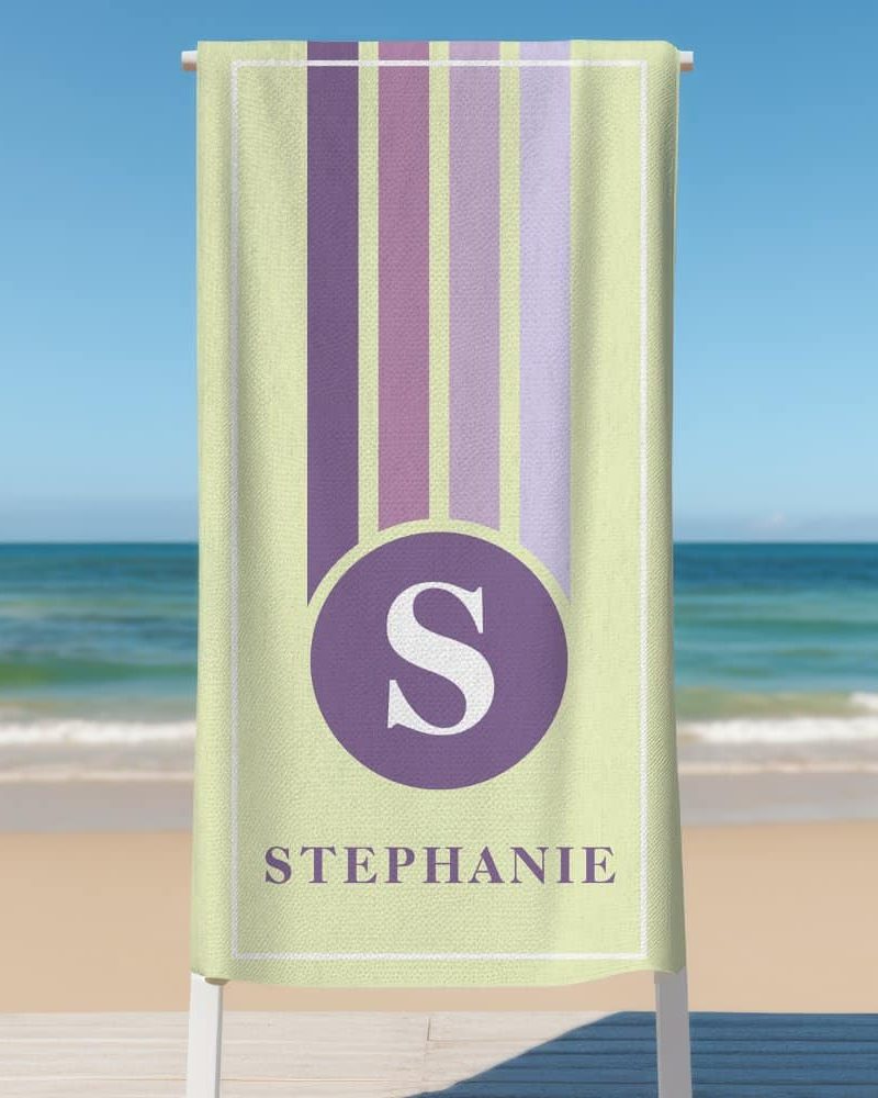 Personalized beach towel with pastel vertical stripes, a purple circle containing the letter S, and the name Stephanie below.