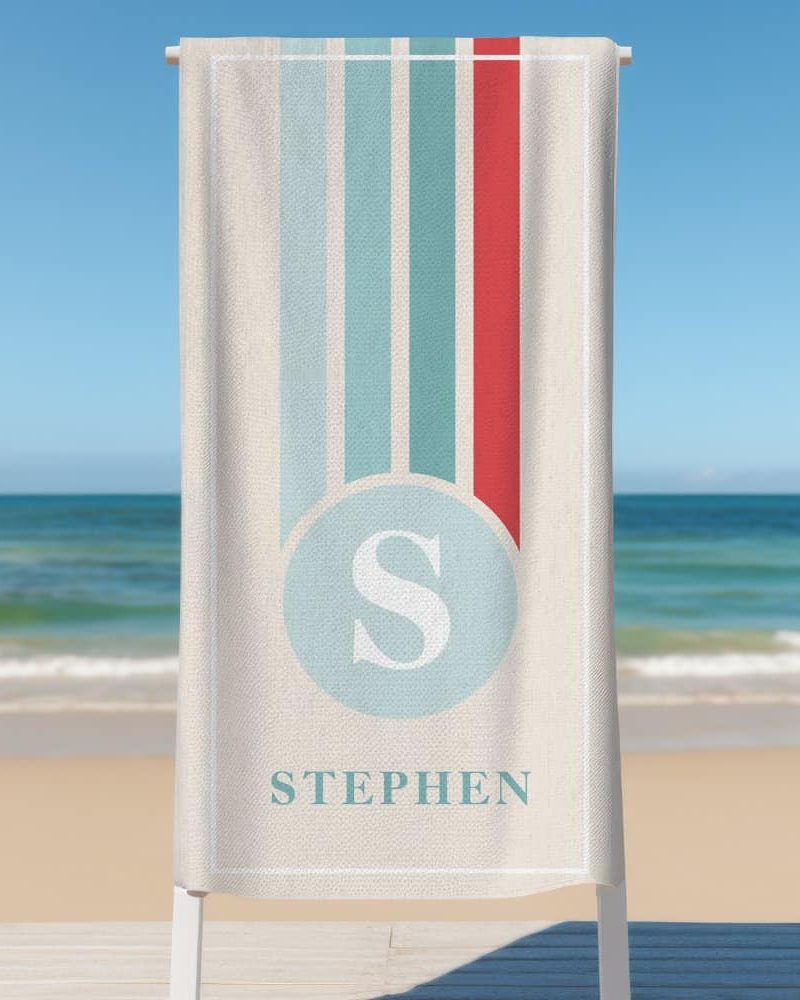 Personalized beach towel with vertical stripes, a circle containing the letter S, and the name Stephen below.