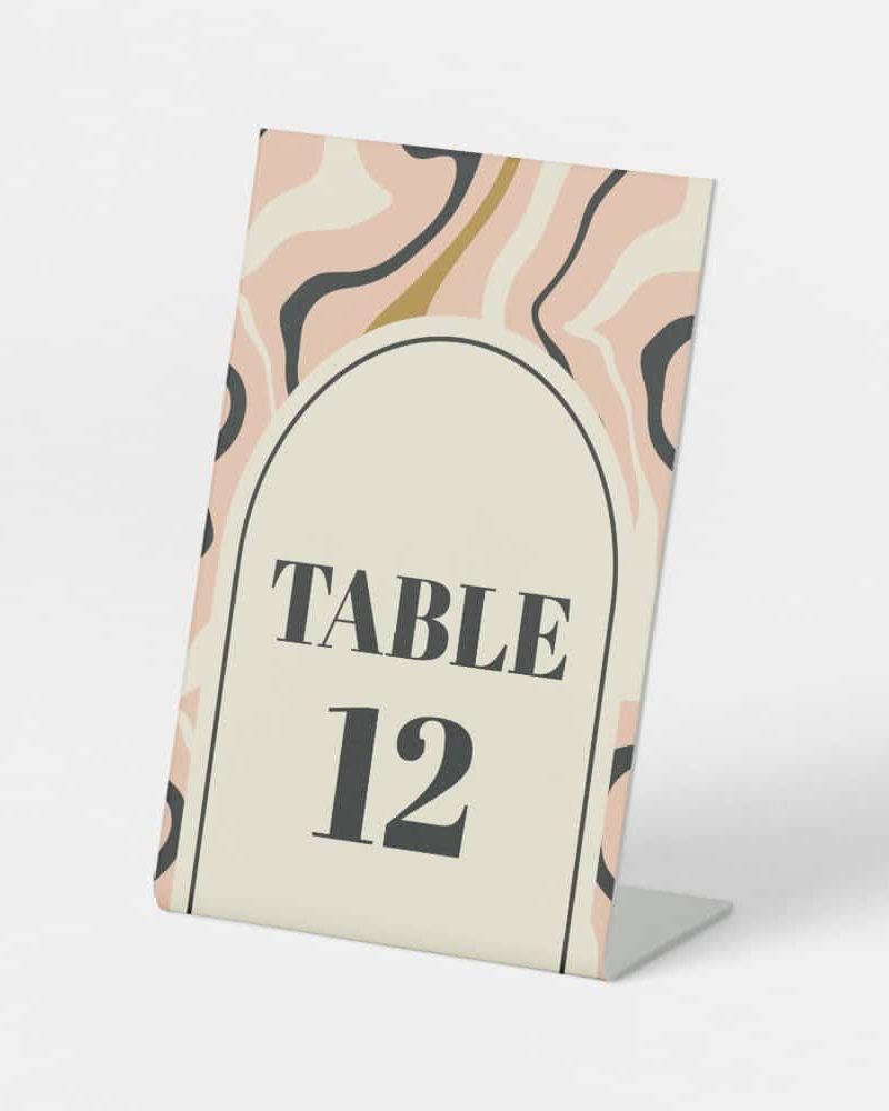 Table number twelve, displayed on a light pink and beige abstract patterned card.