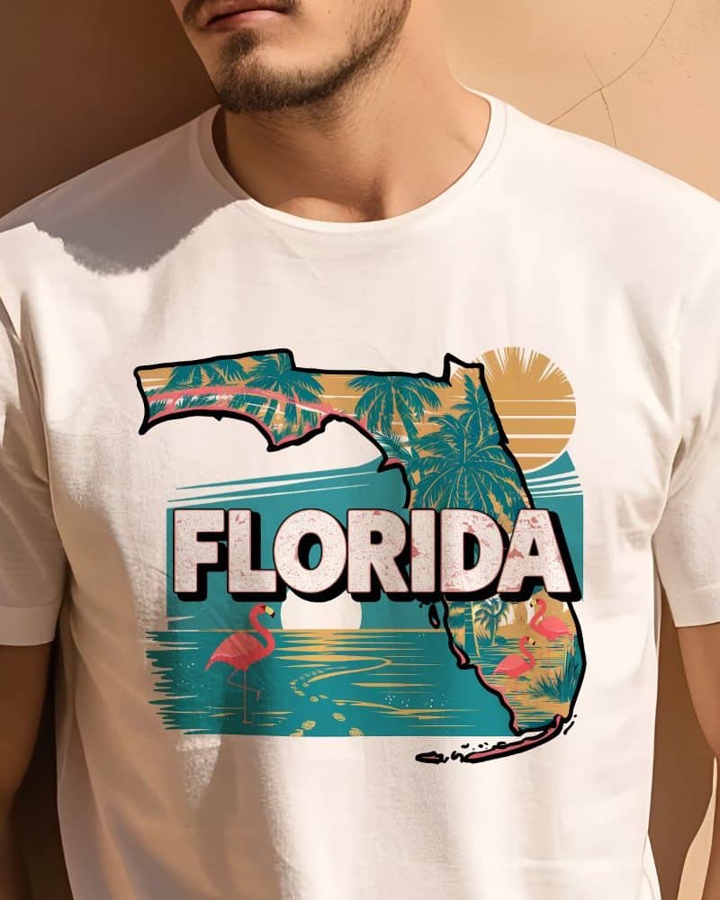 White t-shirt featuring a graphic design of Florida's outline, palm trees, flamingos, and a beach scene.