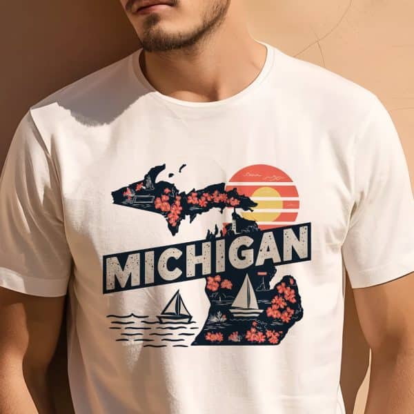 Man Wearing A White T-Shirt Featuring A Graphic Design Of The Michigan State Outline Adorned With Flowers And Sailboats, Set Against A Sunset Backdrop.