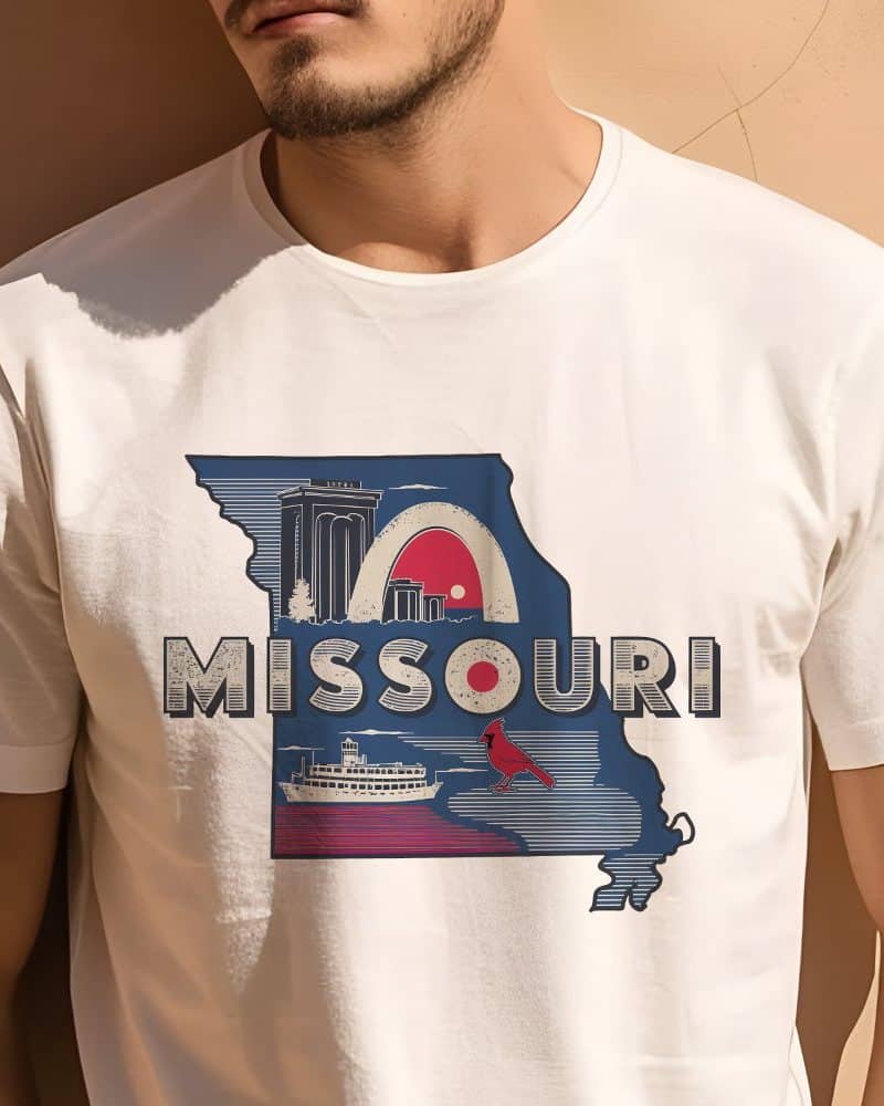 Person wearing a white t-shirt with a graphic design of the state of Missouri, featuring iconic landmarks and a cardinal.
