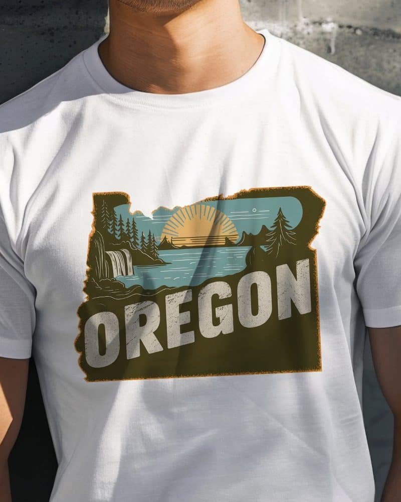 White t-shirt featuring a vintage-style graphic of the Oregon state outline with an illustrated landscape and the word Oregon.