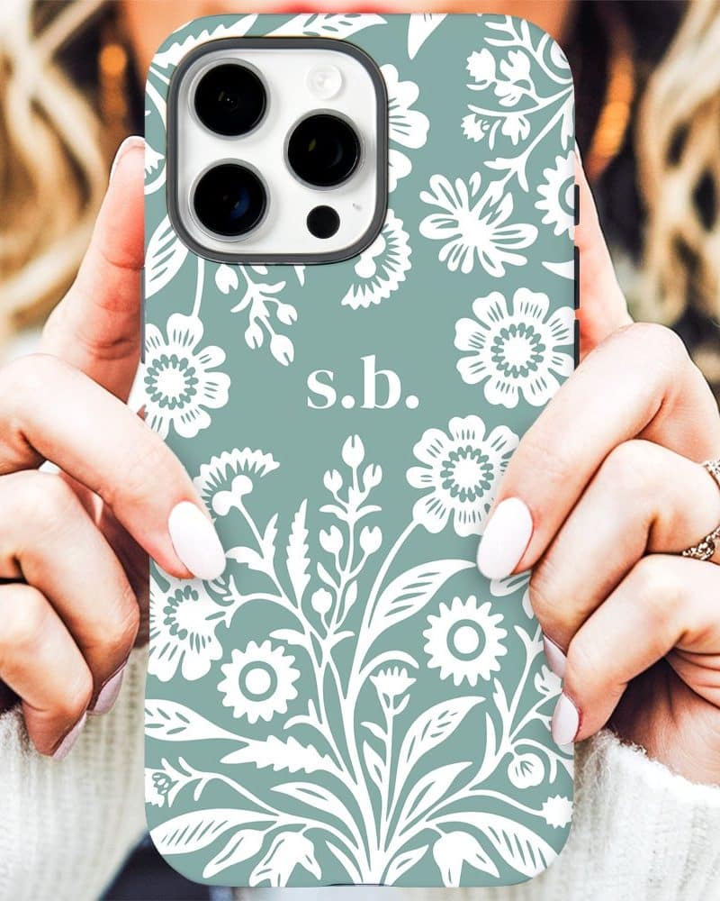 A teal iPhone case with a white floral pattern and the initials sb.