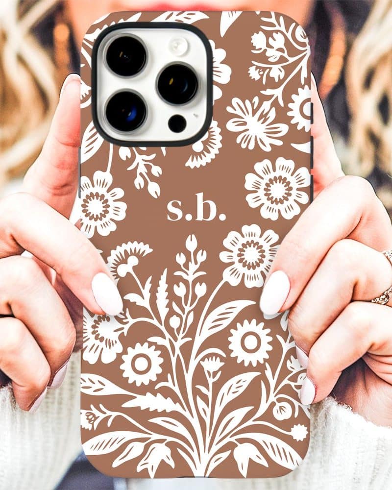 Brown iPhone case with a white floral pattern and initials s.b.