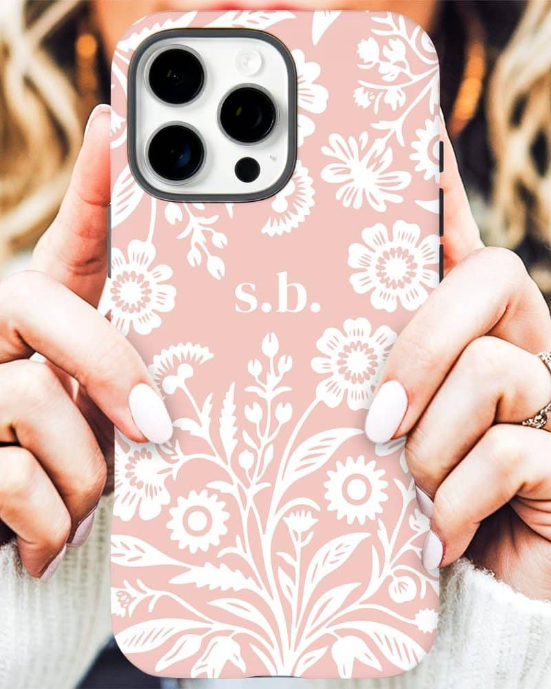 Pink iPhone case with a white floral pattern and initials s.b.