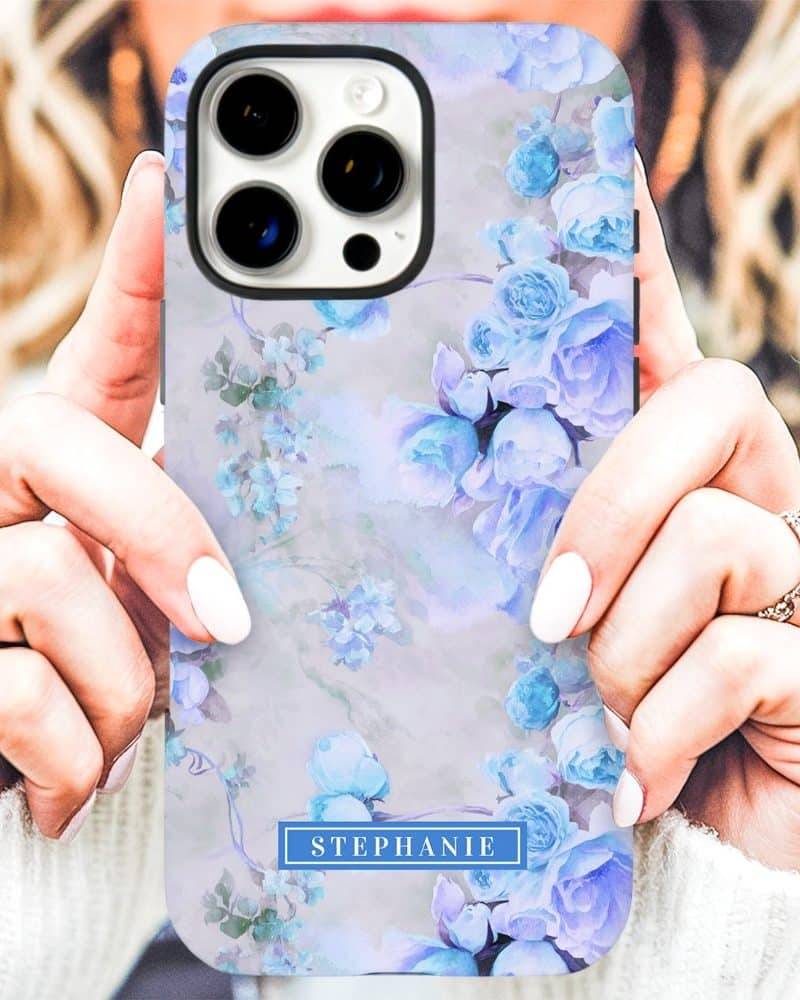Womans hands holding a phone case with a watercolor floral design featuring light blue roses and the name Stephanie.