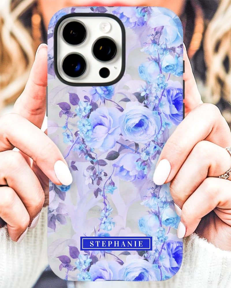 Person holding a phone case with a pale purple and blue floral design and the name Stephanie.