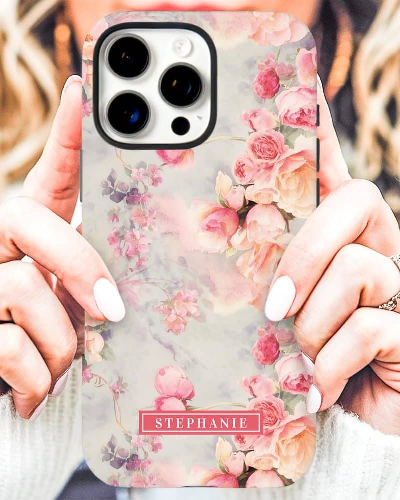 Close-up of hands holding a phone case featuring a watercolor floral design with pastel roses and the name Stephanie.