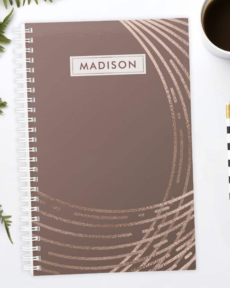 Spiral-bound notebook with a mauve cover featuring rose gold abstract lines and the name Madison.