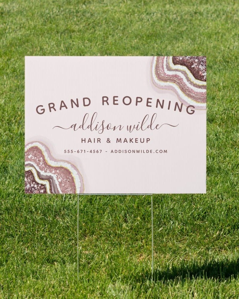 A pink grand reopening sign for Addison Wilde Hair & Makeup. The sign features a geode design.