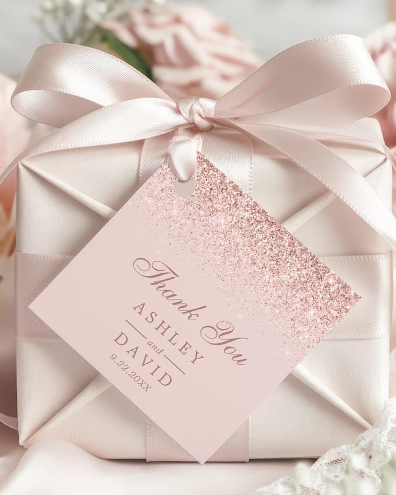A pink gift box with a rose gold glitter thank you tag that says Ashley and David.