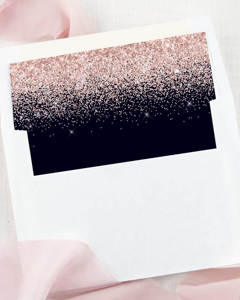 White envelope with a dark navy blue and rose gold glitter liner.