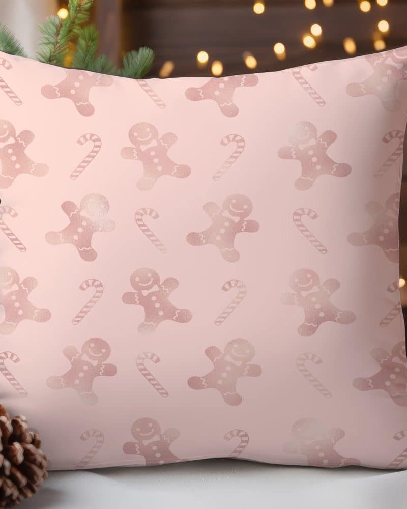 Pink throw pillow with a repeating pattern of rose gold gingerbread men and candy canes.