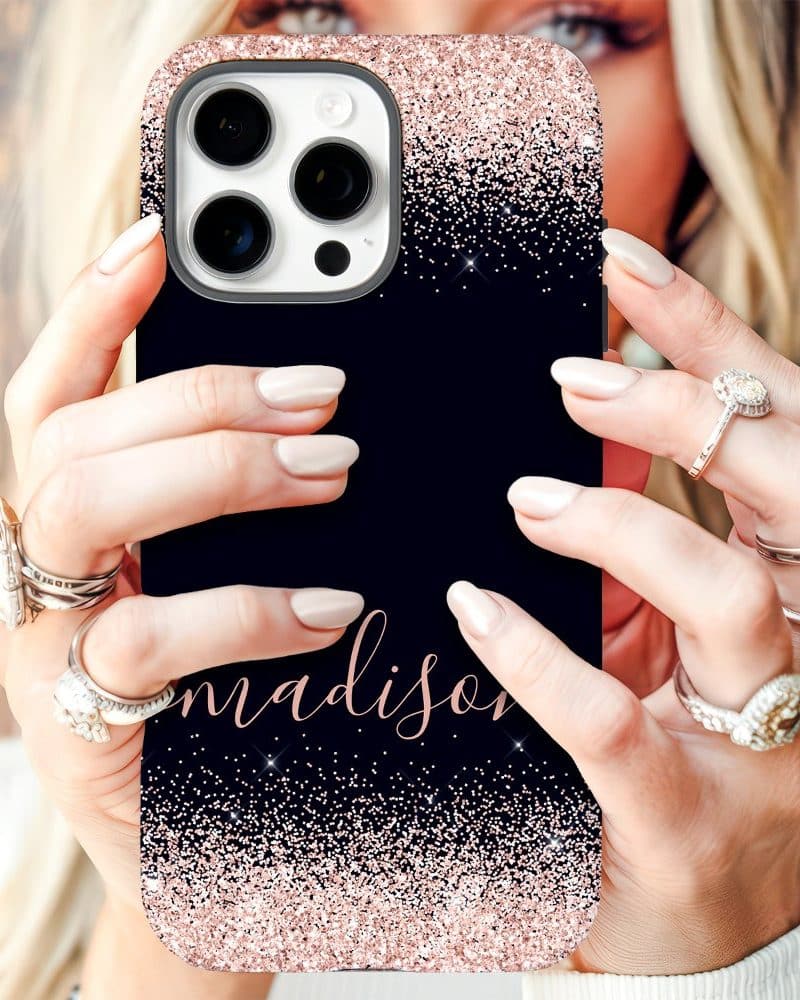 Close-up of hands holding a navy blue iPhone case with rose gold glitter and the name Madison.