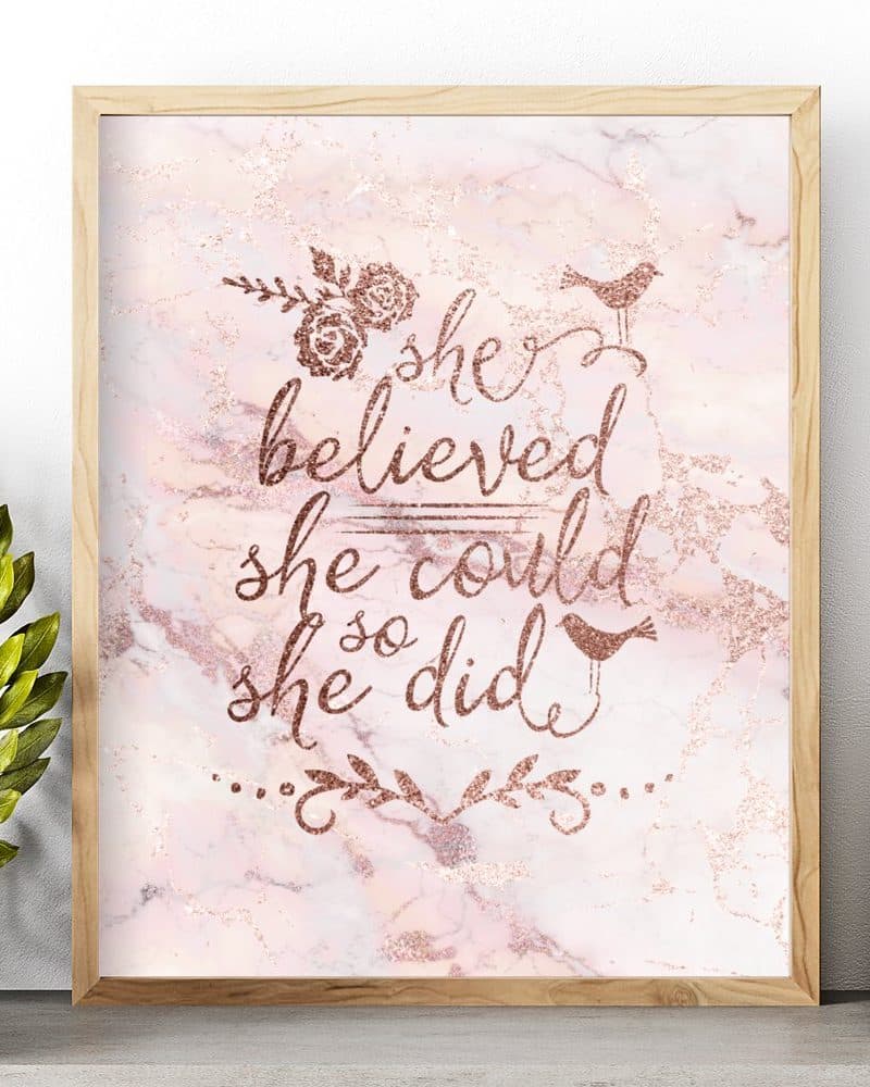Rose gold inspirational quote on a pink marble background framed in light wood. The quote reads She believed she could so she did.