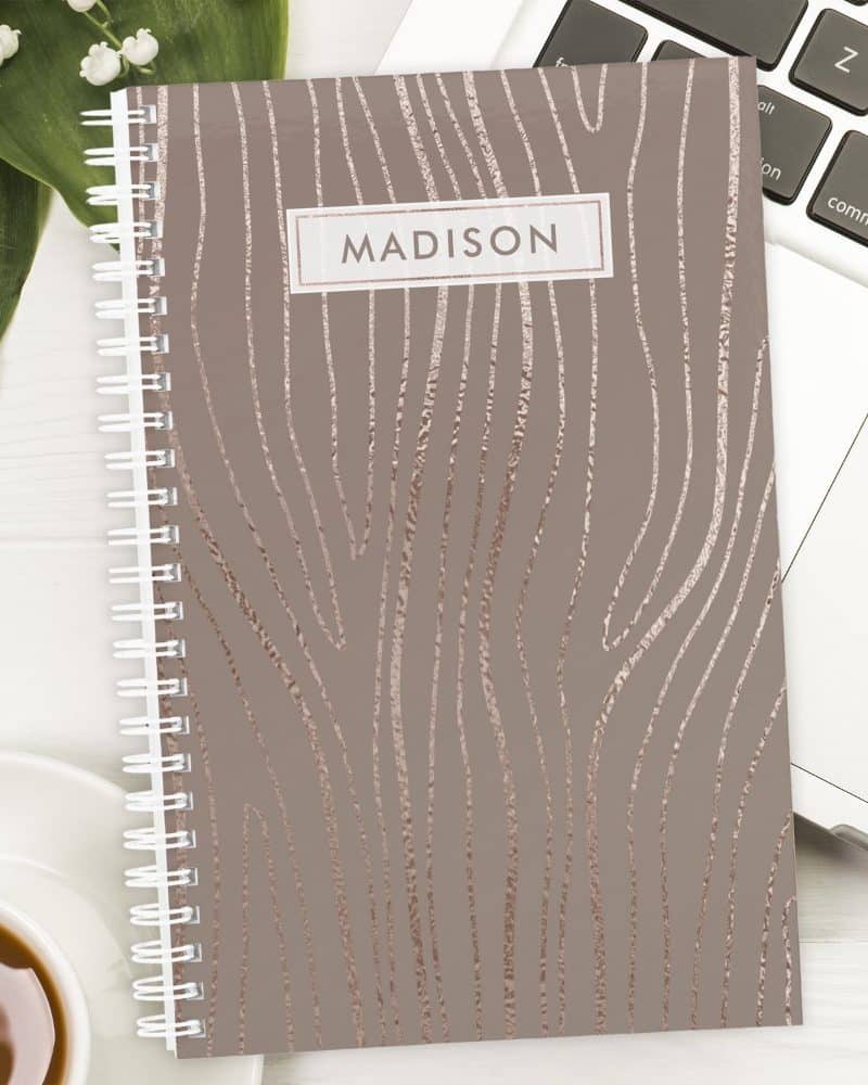 Spiral-bound notebook with a taupe cover and rose gold wood grain design. The name Madison is printed on the cover.