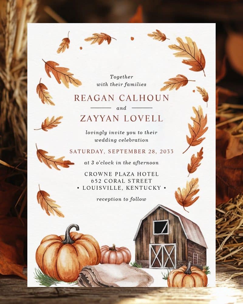 Wedding invitation with autumn leaves, pumpkins, and a barn.