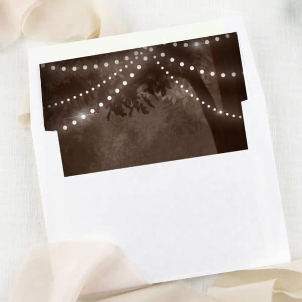White Envelope With A Sepia-Toned Image Of String Lights Draped On A Tree.
