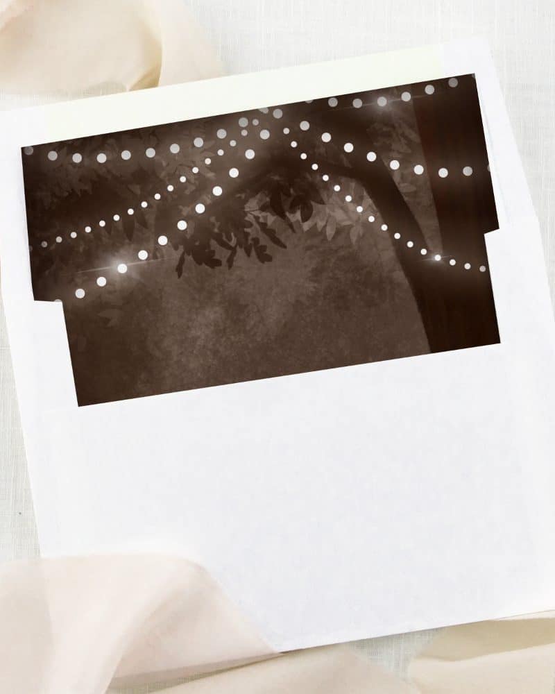 White envelope with a sepia-toned image of string lights draped on a tree.