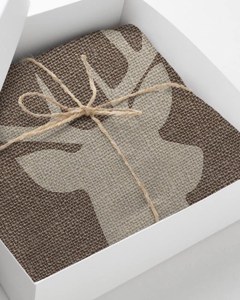 Brown fabric with a beige deer design, tied with twine, in a white gift box.
