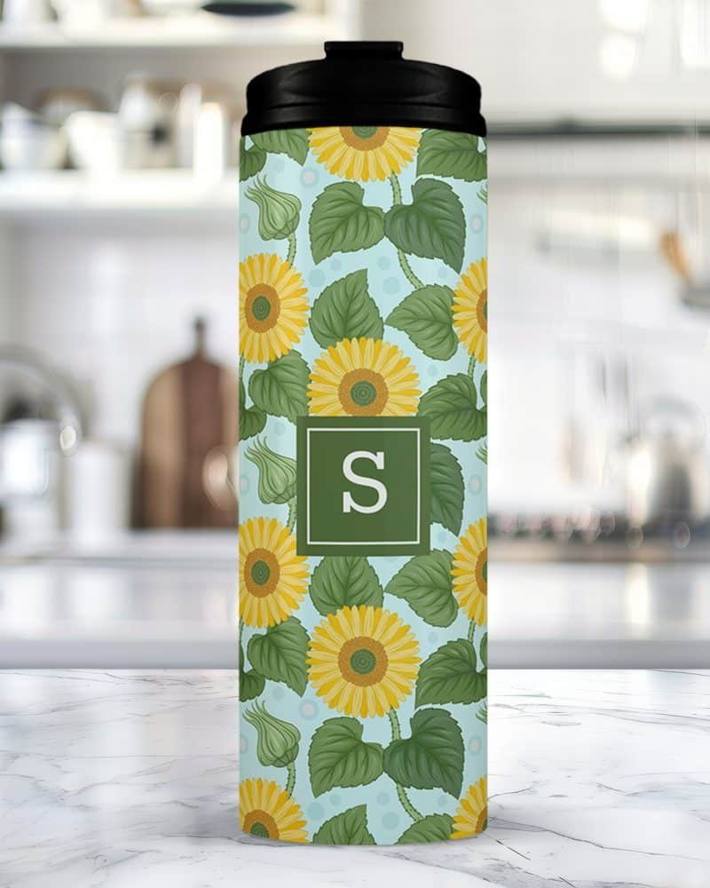 A travel mug with a sunflower and initial S design.