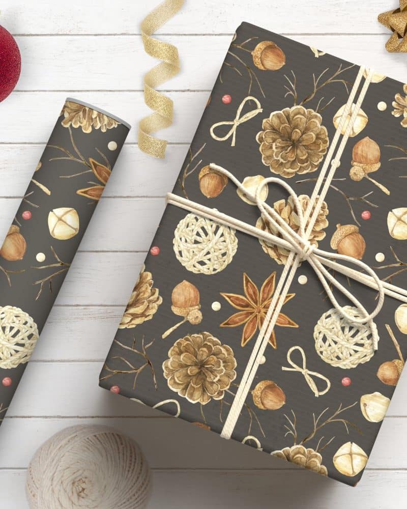 A gift wrapped in dark gray paper with a pattern of pine cones, acorns, and other natural winter elements tied with twine.