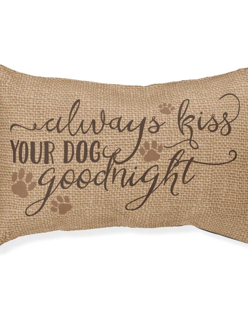 Beige rectangular pillow with the text Always Kiss Your Dog Goodnight. Paw prints are also printed on the pillow.