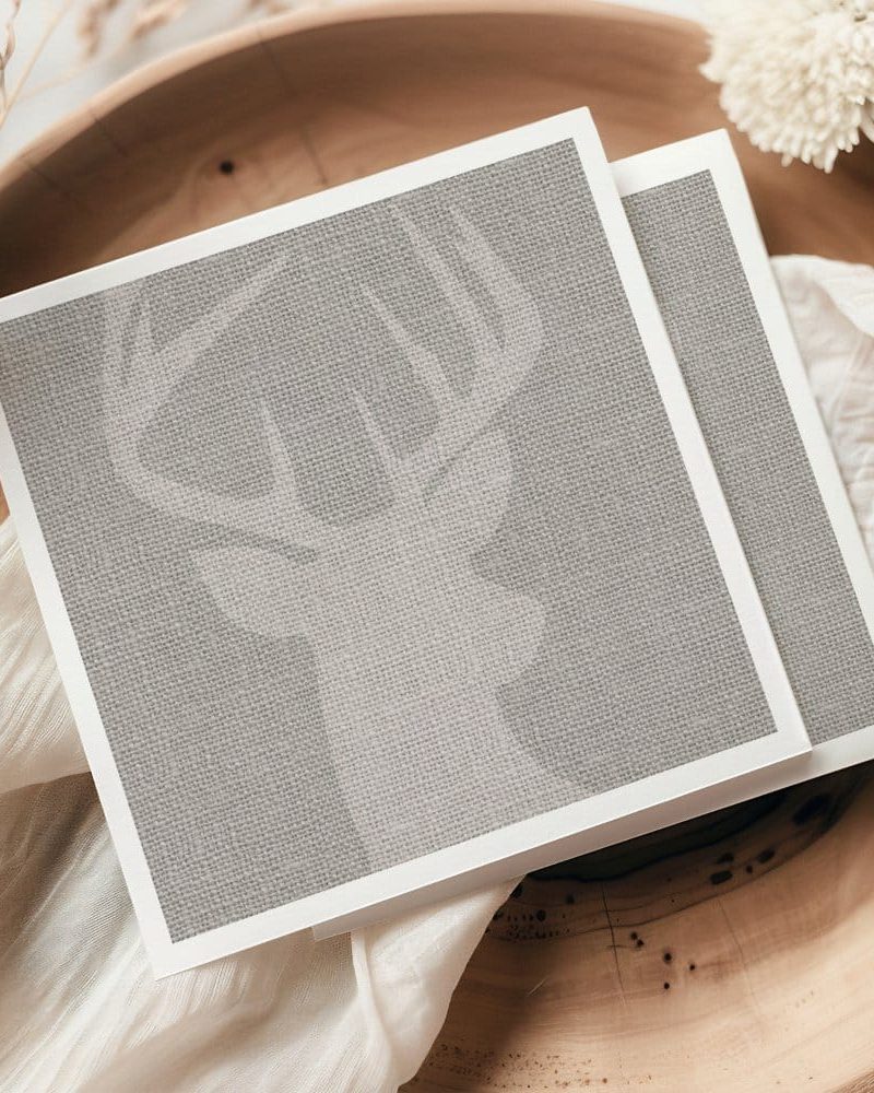 A taupe linen textured card features a subtle, embossed image of a deer's head and antlers.