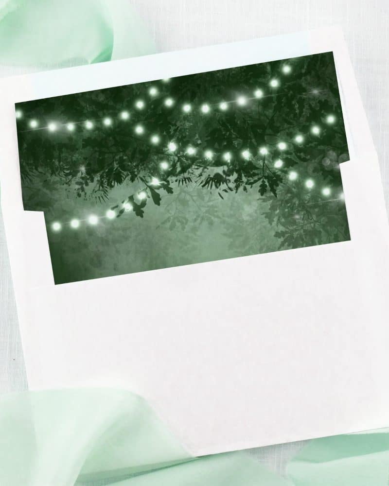 White envelope with a dark green insert showing string lights among tree branches.