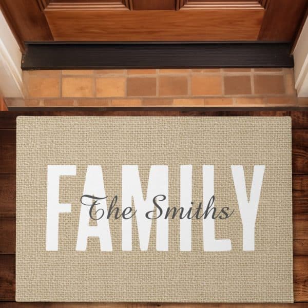 Beige Doormat With The Word Family In Large White Letters, And The Smiths In A Smaller, Cursive Font Underneath.