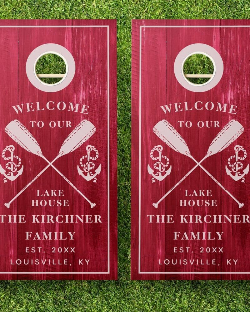 Two red wooden cornhole boards with a welcome message, crossed oars, anchors, and the Kirchner family name and location.